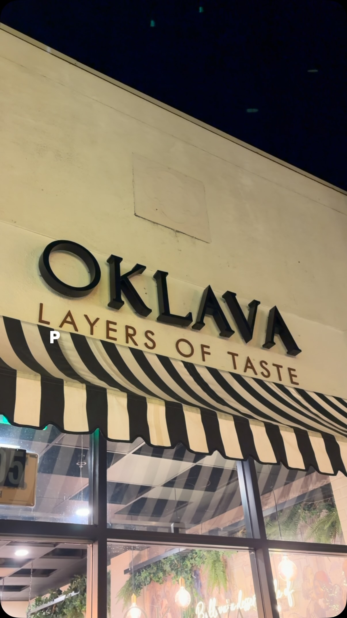 Oklava sign lit up above the awning at night